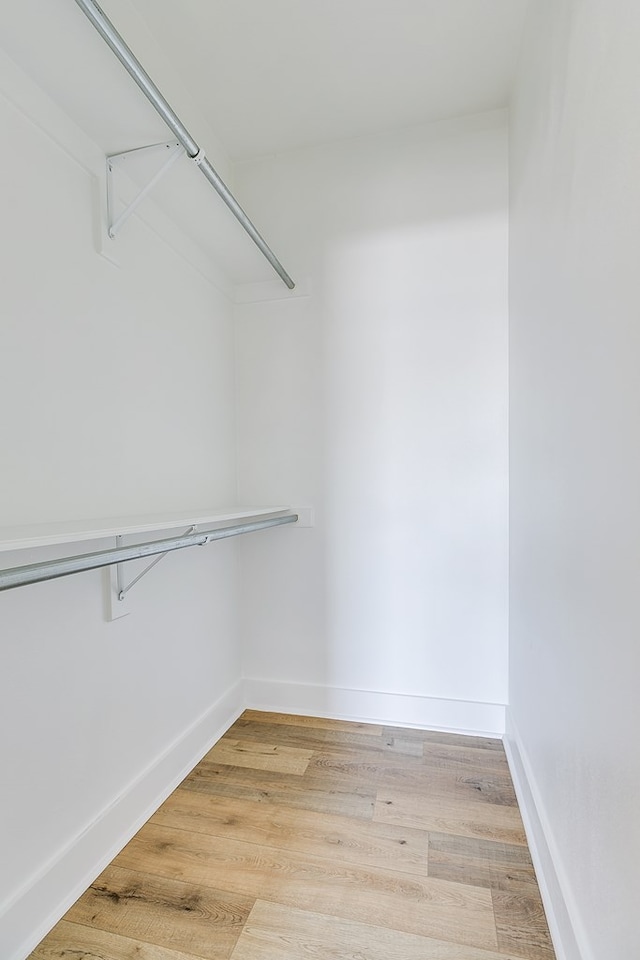 walk in closet with light hardwood / wood-style floors