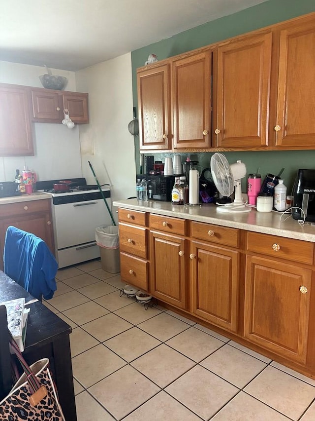 811 Akin St, San Angelo, TX 76901 - kitchen featuring white range with gas cooktop, light tile patterned floors, and brown cabinets