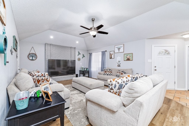 living room with vaulted ceiling, a textured ceiling, ceiling fan, and light hardwood / wood-style floors