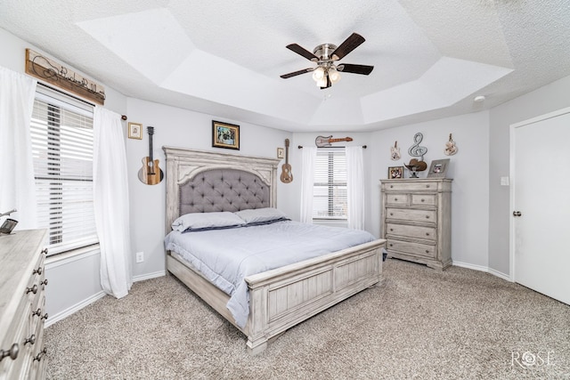 carpeted bedroom featuring ceiling fan, a raised ceiling, and a textured ceiling