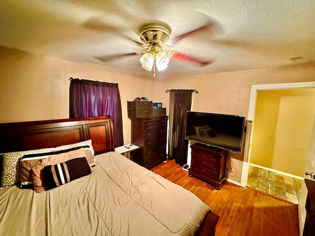 bedroom featuring hardwood / wood-style floors, a textured ceiling, and ceiling fan