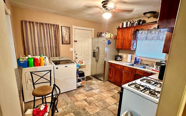 kitchen featuring sink, a textured ceiling, stainless steel fridge, ceiling fan, and white gas range oven