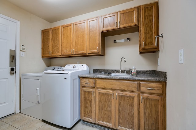 clothes washing area featuring washer and clothes dryer, light tile patterned flooring, cabinet space, and a sink