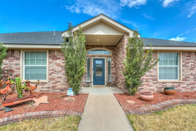 property entrance with brick siding and a shingled roof