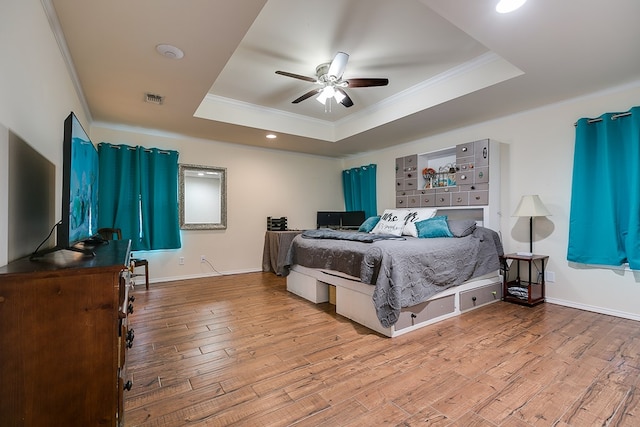 bedroom featuring a raised ceiling, crown molding, wood finished floors, and visible vents