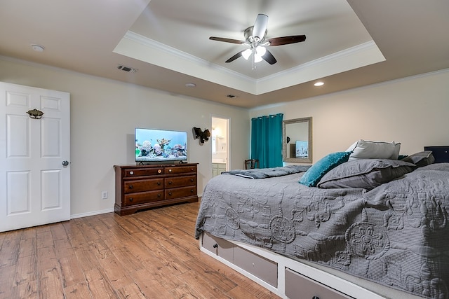 bedroom with visible vents, crown molding, a tray ceiling, and wood finished floors