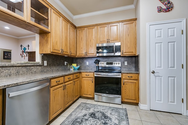 kitchen featuring tasteful backsplash, dark countertops, stainless steel appliances, crown molding, and light tile patterned floors