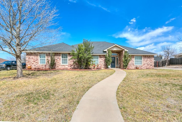 ranch-style home with a front yard, fence, brick siding, and a shingled roof