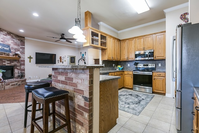 kitchen featuring a breakfast bar area, appliances with stainless steel finishes, light tile patterned flooring, and ornamental molding