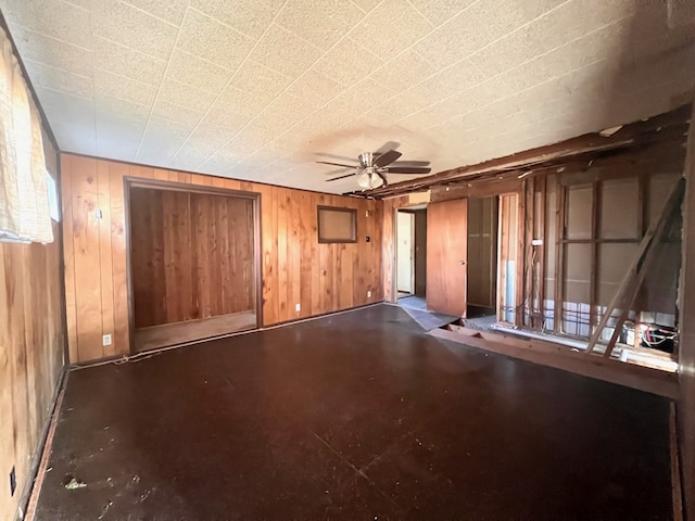 unfurnished room featuring ceiling fan and wood walls