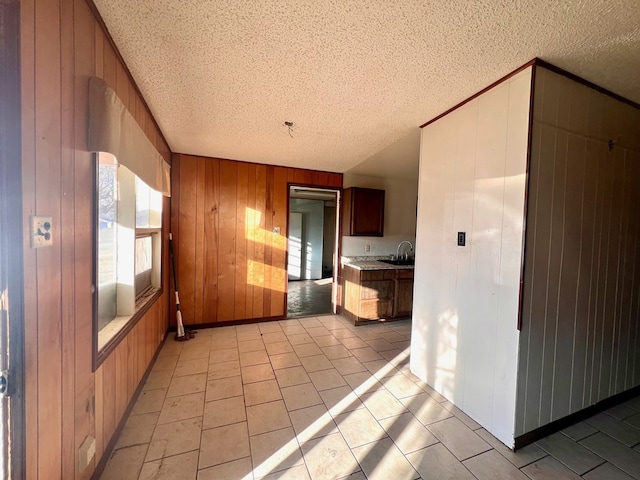 kitchen with sink, a textured ceiling, and wood walls