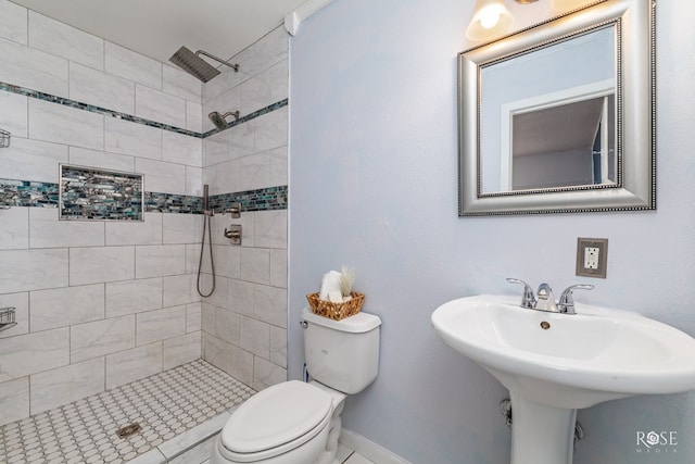 bathroom with sink, a tile shower, and toilet