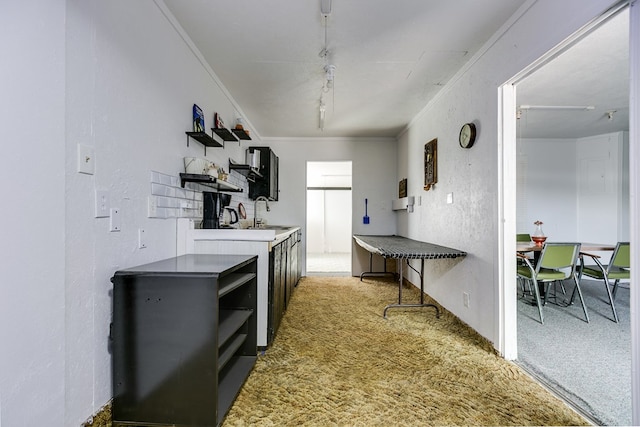 kitchen featuring crown molding, open shelves, light colored carpet, and a textured wall