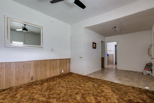 spare room featuring a wainscoted wall, a ceiling fan, and wood walls
