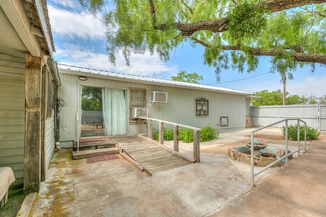 exterior space featuring metal roof, a wall mounted air conditioner, a patio area, fence, and cooling unit