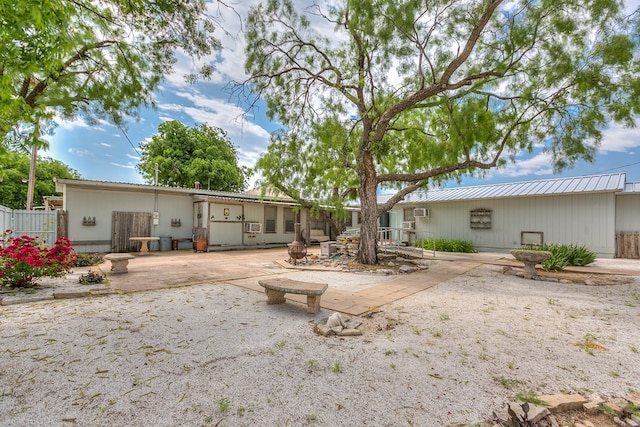 rear view of house with a patio area, fence, and metal roof