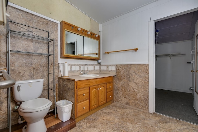 bathroom featuring vanity, toilet, and tile walls