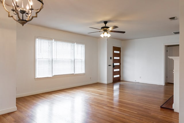 spare room with hardwood / wood-style flooring and ceiling fan with notable chandelier