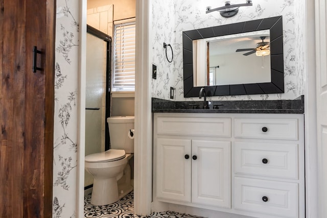 bathroom featuring toilet, vanity, ceiling fan, and a shower with door