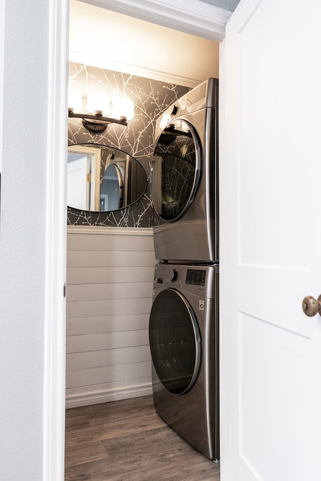 clothes washing area with stacked washer and dryer and wood-type flooring