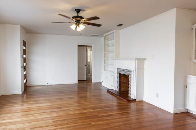 unfurnished living room with built in features, hardwood / wood-style flooring, and ceiling fan