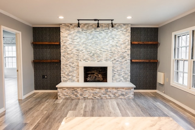 unfurnished living room featuring a fireplace, crown molding, rail lighting, and hardwood / wood-style floors