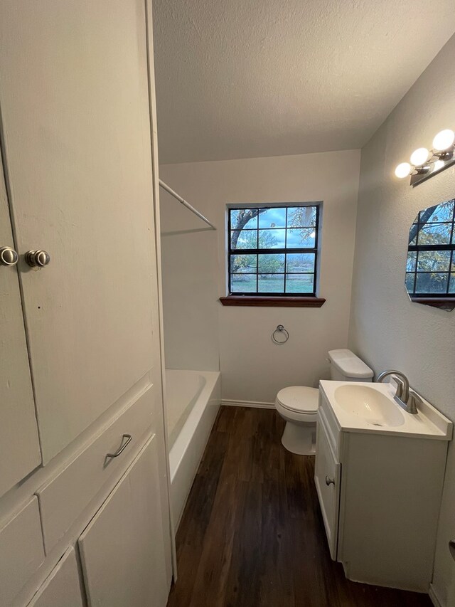 20 E 39th St, San Angelo, TX 76903 - full bathroom with wood finished floors, plenty of natural light, vanity, toilet, and a textured ceiling