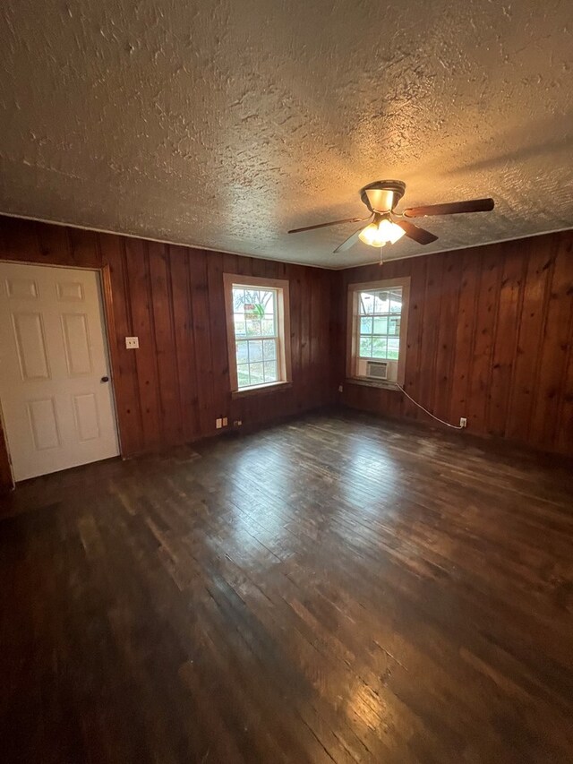 20 E 39th St, San Angelo, TX 76903 - unfurnished room with dark wood finished floors, a ceiling fan, a textured ceiling, and wood walls