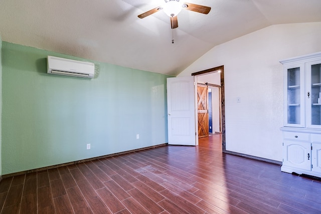 spare room with dark hardwood / wood-style flooring, lofted ceiling, an AC wall unit, and a barn door