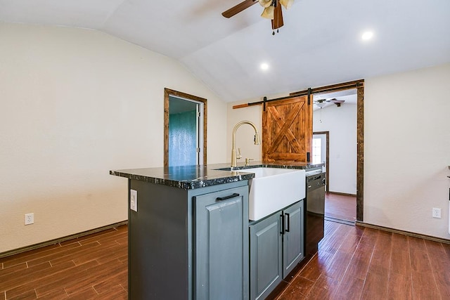 kitchen with lofted ceiling, gray cabinetry, black dishwasher, an island with sink, and a barn door