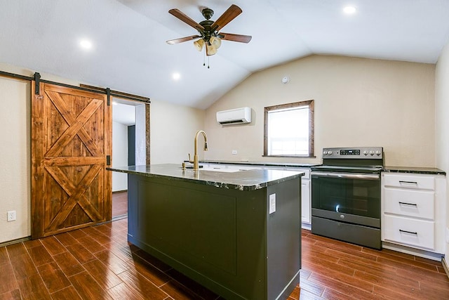 kitchen with sink, stainless steel range with electric cooktop, an AC wall unit, an island with sink, and a barn door