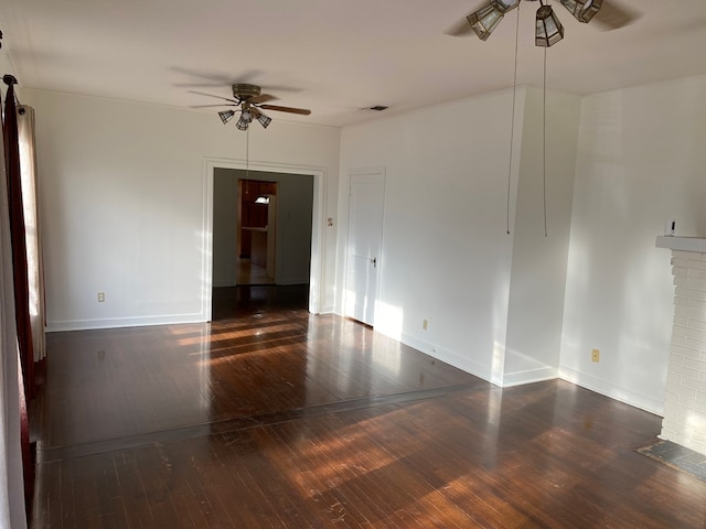 unfurnished room featuring dark hardwood / wood-style flooring, a fireplace, and ceiling fan