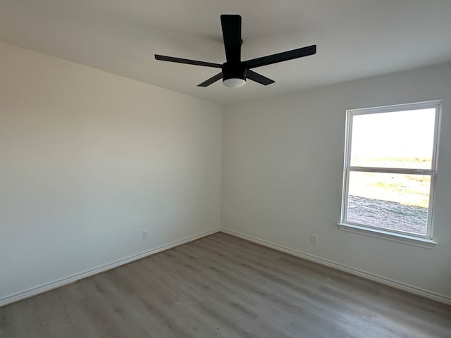 spare room with light wood-type flooring, ceiling fan, and baseboards