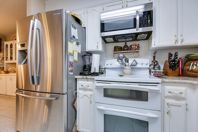 1027 Butterfly Ln, San Angelo, TX 76905 - kitchen with stainless steel appliances, white cabinetry, and light tile patterned floors