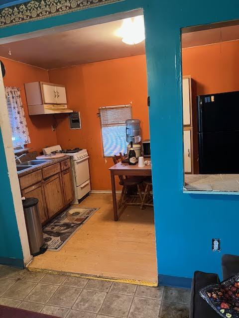 8523 Runion Rd, San Angelo, TX 76905 - kitchen featuring freestanding refrigerator, white gas stove, a sink, brown cabinets, and baseboards