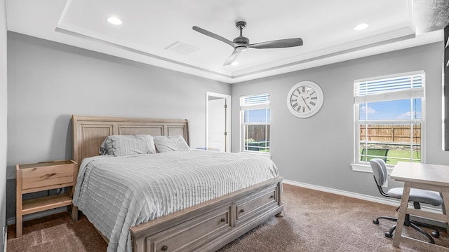 bedroom featuring multiple windows, a tray ceiling, and ceiling fan