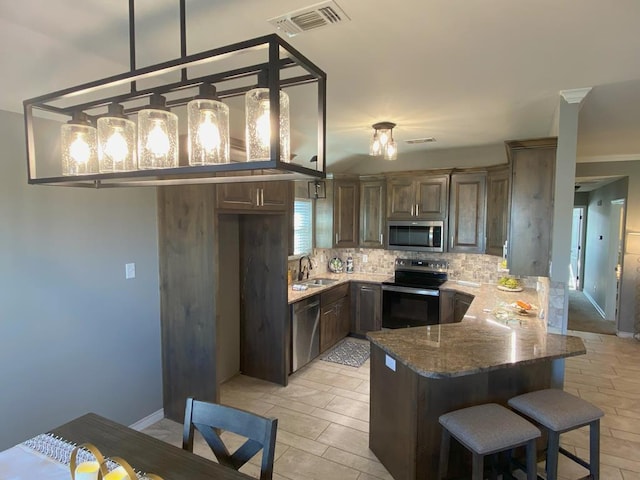 kitchen with sink, decorative light fixtures, stainless steel appliances, light stone countertops, and backsplash