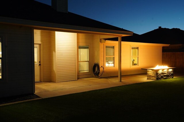 rear view of property featuring an outdoor fire pit and a patio