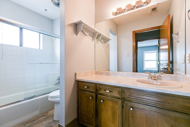 full bathroom with vanity, wood-type flooring, enclosed tub / shower combo, and toilet