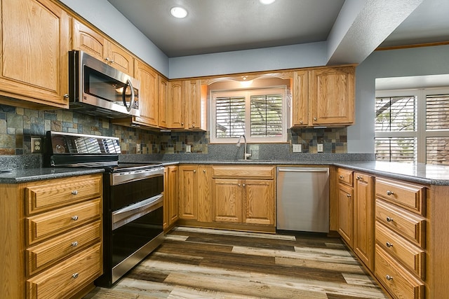 kitchen with tasteful backsplash, appliances with stainless steel finishes, sink, and dark hardwood / wood-style floors