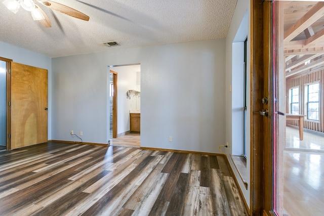 unfurnished bedroom with ensuite bathroom, wood-type flooring, ceiling fan, and a textured ceiling