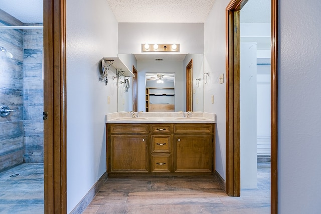 bathroom featuring vanity, wood-type flooring, a textured ceiling, and walk in shower