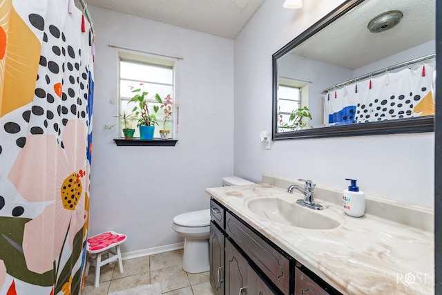 bathroom with baseboards, plenty of natural light, toilet, and vanity
