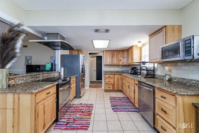 kitchen with tasteful backsplash, a sink, stainless steel appliances, wall chimney exhaust hood, and visible vents