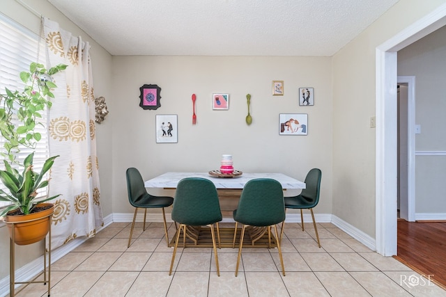 dining area featuring baseboards, a textured ceiling, and light tile patterned floors