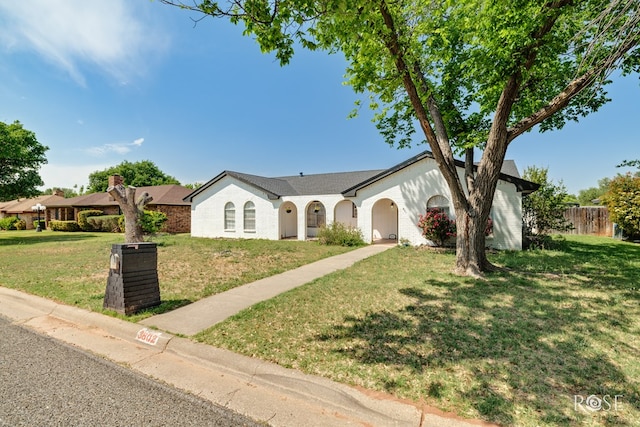 ranch-style house featuring fence, a front lawn, and brick siding