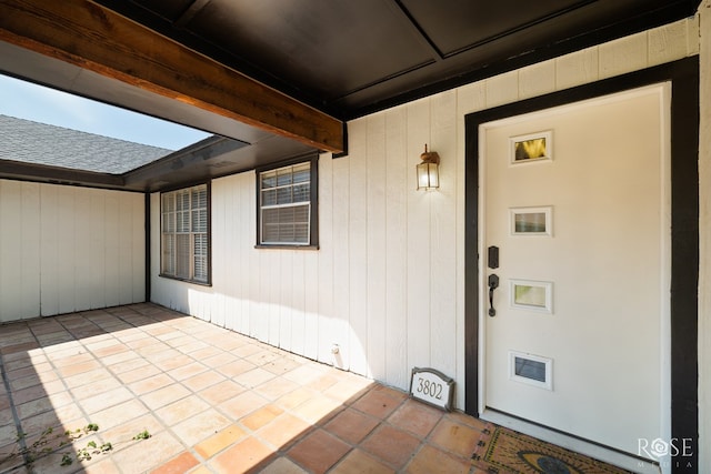 doorway to property with roof with shingles