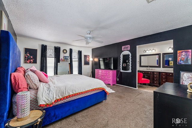 carpeted bedroom with ceiling fan, a textured ceiling, ensuite bathroom, and a sink
