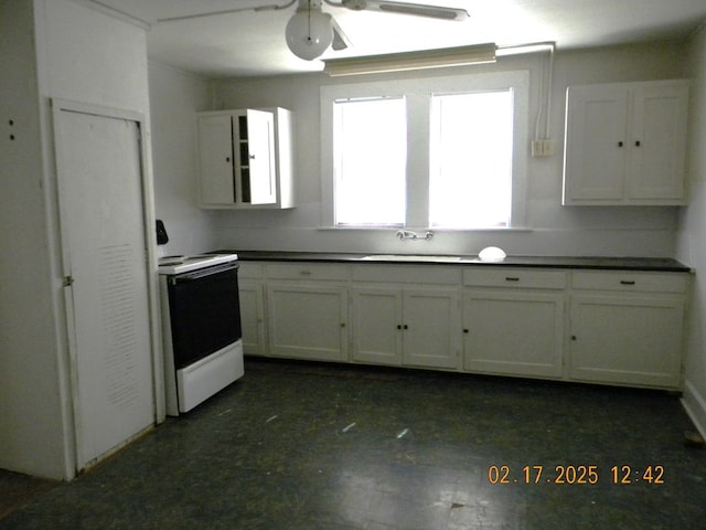 kitchen with electric stove, sink, white cabinets, and ceiling fan