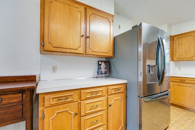 3305 Sierra Ct, San Angelo, TX 76904 - kitchen with stainless steel fridge, light countertops, wallpapered walls, and brown cabinets